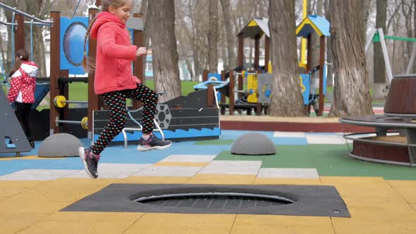 Amazed Young Lady Jumps on Black Trampoline on Playground