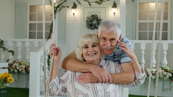 Senior Couple Together in Front Yard at Home. Man Swinging and Hugging Woman. Happy Mature Family