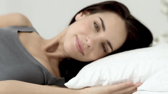 Young woman lying in bed turning to look at camera