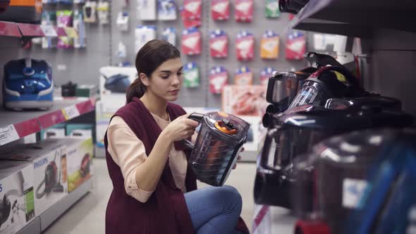 Female Costumer Choosing New Vacuum Cleaner in Appliance Store