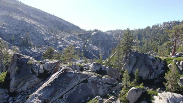 A cienmatic 4K high resolution drone shot flies past a tree line to reveal a deep clear water alpine