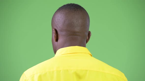 Rear View Head Shot of Young Happy African Businessman Wearing Yellow Shirt and Looking Back