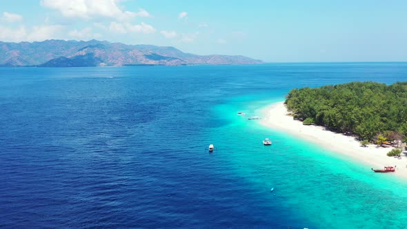 Wide flying travel shot of a white sandy paradise beach and blue sea background in colourful 4K