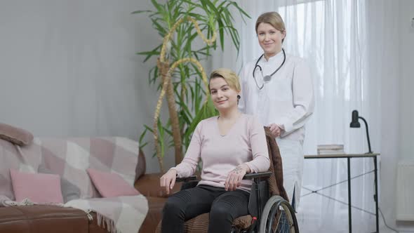 Beautiful Positive Disabled Young Woman Looking at Camera Showing Thumb Up with Smiling Nurse