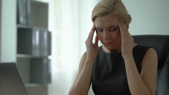 Tired Female Boss Sitting at Office Table, Suffering From Headache and Tension