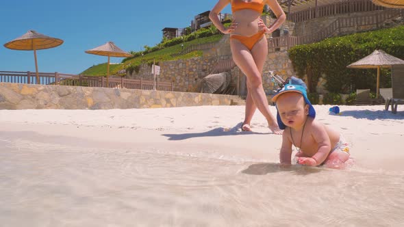 For the First Time, a Child Near the Ocean with His Mother Touches Salt Water 