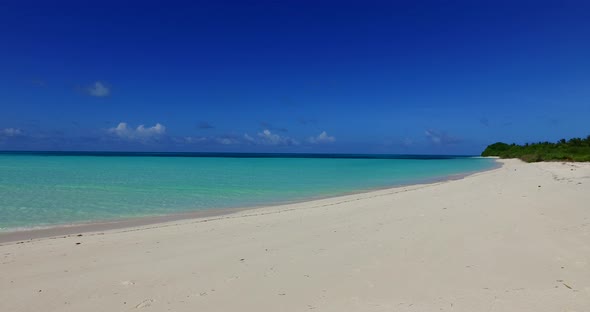 Wide angle fly over island view of a white sand paradise beach and turquoise sea background in color