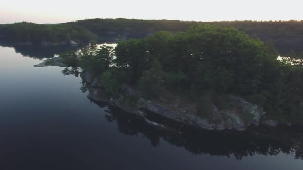 Orbital drone shot around an island in Charletson Lake in Ontario, Canada at sunset