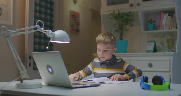 Preschool Child Showing Notebook To Laptop Screen While Studying Online at Home