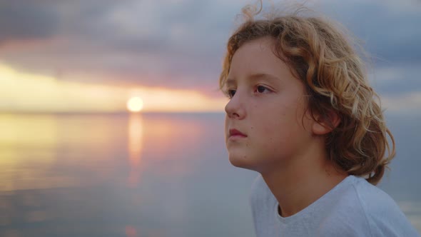 Attractive Boy Looks at the Camera Against the Backdrop of a Beautiful Sunset