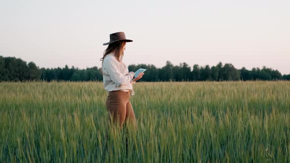 Farmer Girl Works with a Tablet on a Wheat Field, Plans a Grain Harvest, Woman Agronomist 