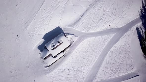 Aerial of ski resort at sun mountains with pine forest. Skiers ride down on snow slope at lifts. Win