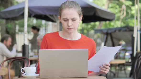 Young Woman Reading Contract and Using Laptop, Sitting Outdoor