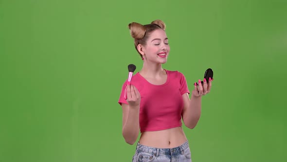 Teen Girl Holding a Brush in Her Hand and Powdering Her Cheeks. Green Screen. Slow Motion