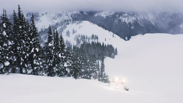 Snowcat Grooming Slope At Ski Resort At Dusk Aerial Overview