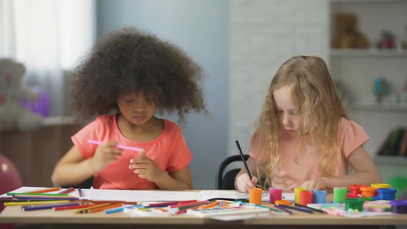 Early education, two multi-ethnic female kids drawing with colorful pencils