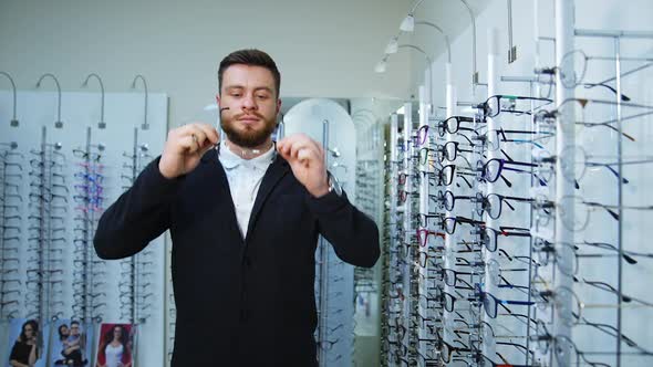 Man choosing glasses in optics store. Young attractive man testing new glasses