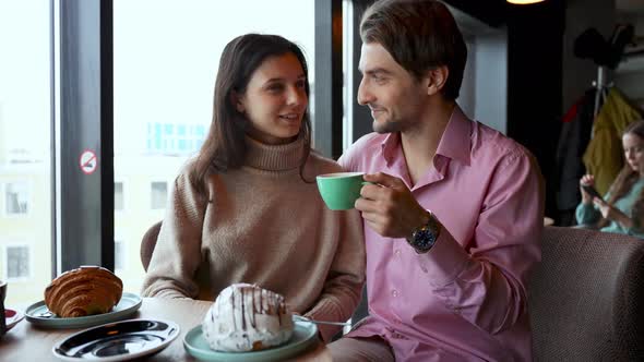 A Young Couple in a Cafe are Chatting and Discussing Where They Will Go on Vacation