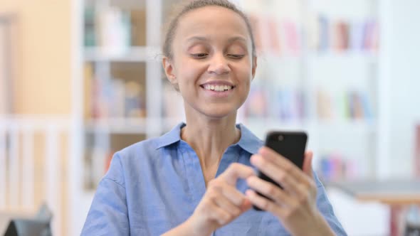 Portrait of African Woman Celebrating Success on Smartphone