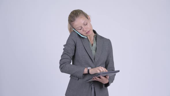 Young Happy Blonde Businesswoman Talking on the Phone While Using Digital Tablet