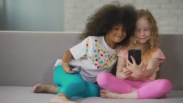 Multiracial Sisters Sitting on Sofa and Taking Selfie on Smartphone at Home