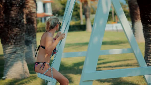 Vacation Holidays Weekend. Swing Ride On Beach Relax.Tanned Woman In Bikini.