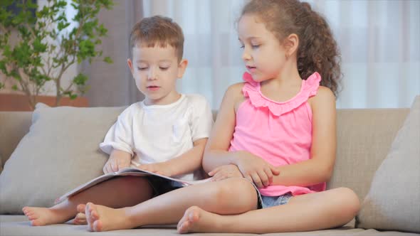 Cute Children,sister with a Younger Brother, Looking at a Book Magazine Textbook Dictionary Tablet