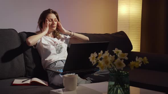 Young woman working on laptop alone in dark living