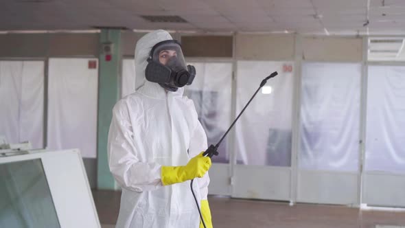 Disinfector in Special Clothes and in a Protective Mask with a Sprayer