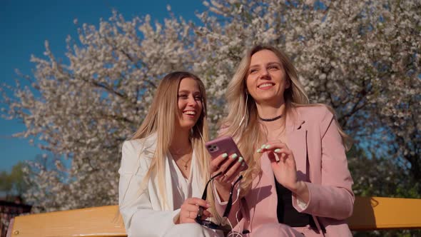 Girls using cellphone for having fun outdoors. Friendship concept