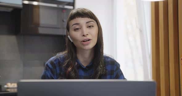 Portrait of a Young Girl in Headphones Talking in Front of a Laptop