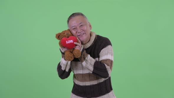 Happy Mature Japanese Man Giving Teddy Bear