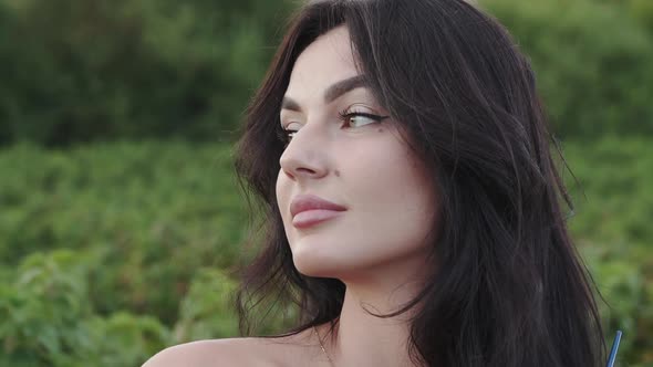 Portrait of Gorgeous Brunette with Brush in Hand Looking Aside and Smiling