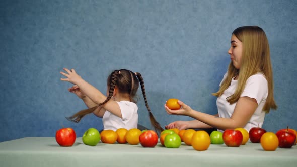 Happy mother and daughter play with fruit. 