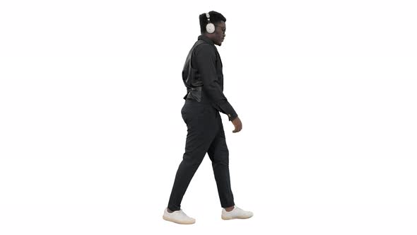 Young African American Man Listening To Music in Headphones While Walking on White Background