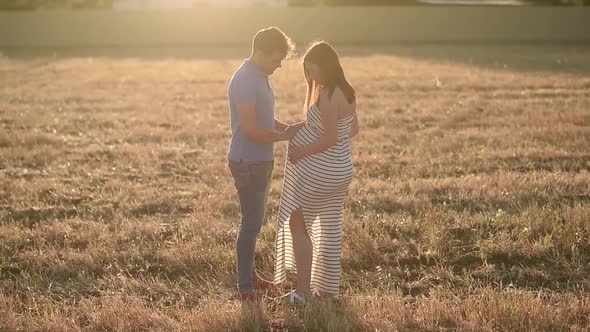 Pregnant couple in a hay field