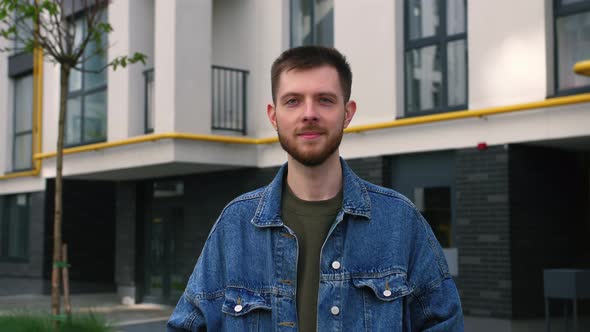 Portrait of a Smiling Young Professional Man Standing in Front of Corporate Building Looking at