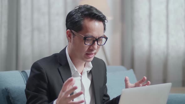 Close Up Of Asian Businessman In Jacket And Shorts Having Video Call On A Laptop At Home