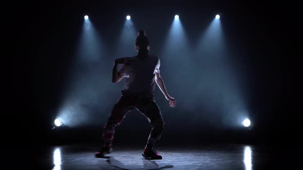 Man Enjoying Hip Hop Moves in Dark Studio with Smoke and Lighting.