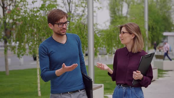 Man and woman walk outside talking about business.