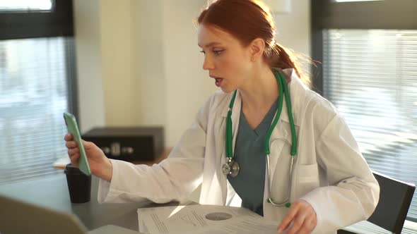 Professional Female Doctor Having Video Call Via Mobile Phone Giving Distant Online Consultation to