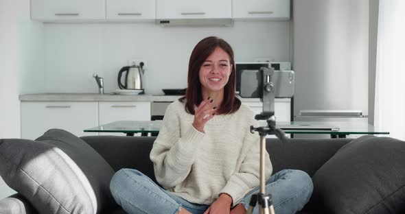 Woman Sitting in Couch Recording New Videovlog Puts Smartphone on Tripod