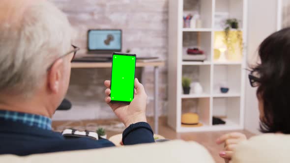 Back View of Elderly Age Couple Holding Phone