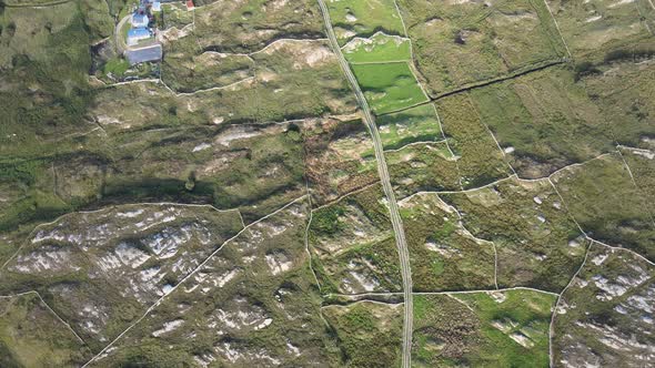 Lush Farmland Surrounded By Rocky Fields In Connemara, Ireland On A Sunny Day - top-down aerial shot