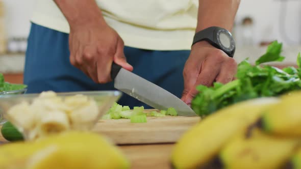 Fit african american man cooking, preparing healthy green smoothie