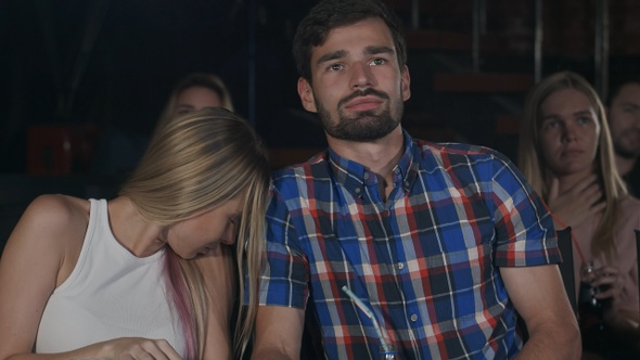 Young couple watching horror movie in cinema girl turning