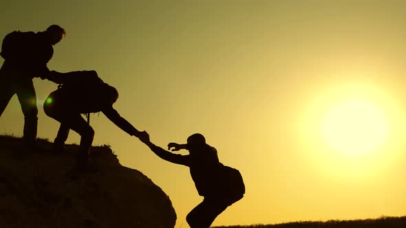 Climbers Silhouettes Stretch Their Hands To Each Other, Climbing To the Top of the Hill. Travelers