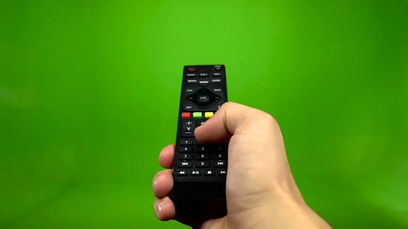 Male Hand Operating a Tv Remote Control on a Green Screen