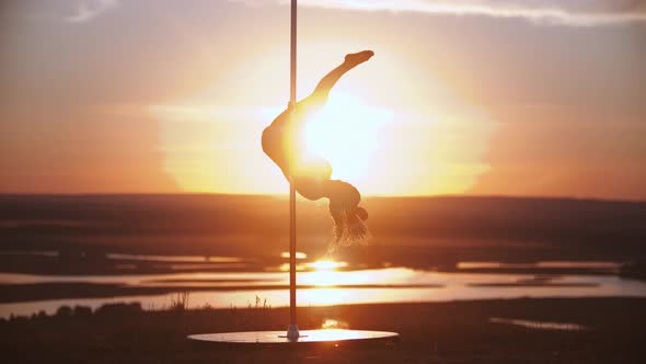 Young Woman Jumping on the Dancing Pole on Sunset