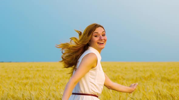 Young Smiling Red Haired Woman Running in Wheat Field at Sunset